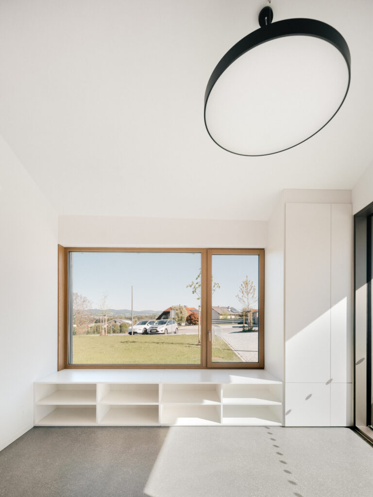 Heller Eingangsbereich mit weißem Wandverbau mit Sitzfenster aus Holz
